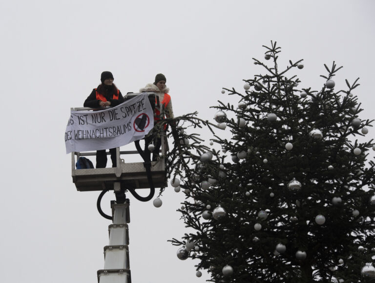 21.12.2022, Berlin: Ohne Spitze steht der Weihnachtsbaum vor dem Brandenburger Tor. Zwei Aktivisten der Umweltschutzgruppe fuhren mit einem Hubwagen vor dem Tannenbaum auf dem Pariser Platz am Brandenburger Tor. Sie entrollten ein Transparent und entfernten dann die Spitze des Weihnachtsbaums. Foto: Paul Zinken/dpa +++ dpa-Bildfunk +++ (KEYSTONE/DPA/Paul Zinken)