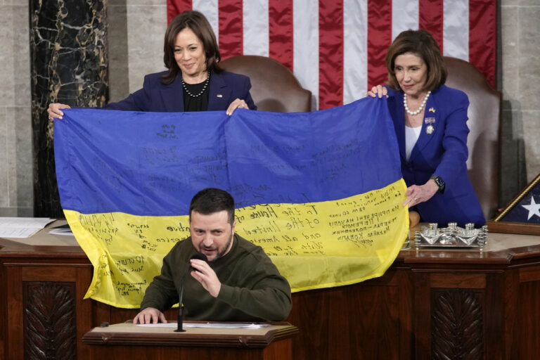 Vice President Kamala Harris and House Speaker Nancy Pelosi of Calif., right, hold a Ukrainian flag autographed by front-line troops in Bakhmut, in Ukraine's contested Donetsk province, that Ukrainian President Volodymyr Zelenskyy presented to lawmakers while addressing a joint meeting of Congress on Capitol Hill in Washington, Wednesday, Dec. 21, 2022. (AP Photo/Carolyn Kaster)