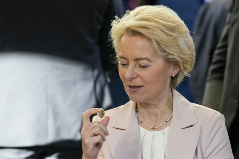 Ursula von der Leyen, President of the European Commission, inspects a Croatian euro coin at a cafe in Zagreb, Sunday, Jan. 1, 2023. Croatia switched to the shared European currency, the euro, and removed dozens of border checkpoints to join the world's largest passport-free travel area. (AP Photo/Darko Bandic)