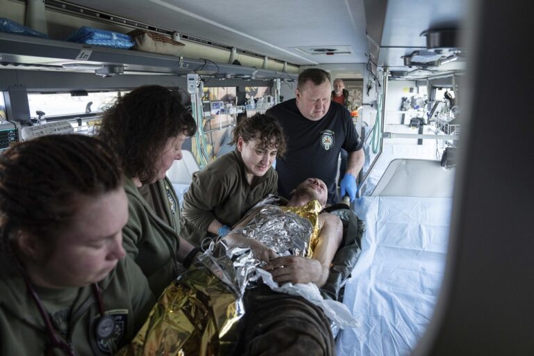 Volunteers of Hospitallers paramedic organisation move an injured Ukrainian soldier inside a special medical bus during evacuation in Donetsk region, Ukraine, Wednesday, March 22, 2023. (AP Photo/Evgeniy Maloletka)