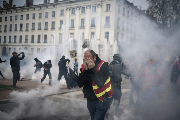 Protesters run amid the tear gas during a demonstration in Lyon, central France, Thursday, March 23, 2023. French unions are holding their first mass demonstrations Thursday since President Emmanuel Macron enflamed public anger by forcing a higher retirement age through parliament without a vote. (AP Photo/Laurent Cipriani)