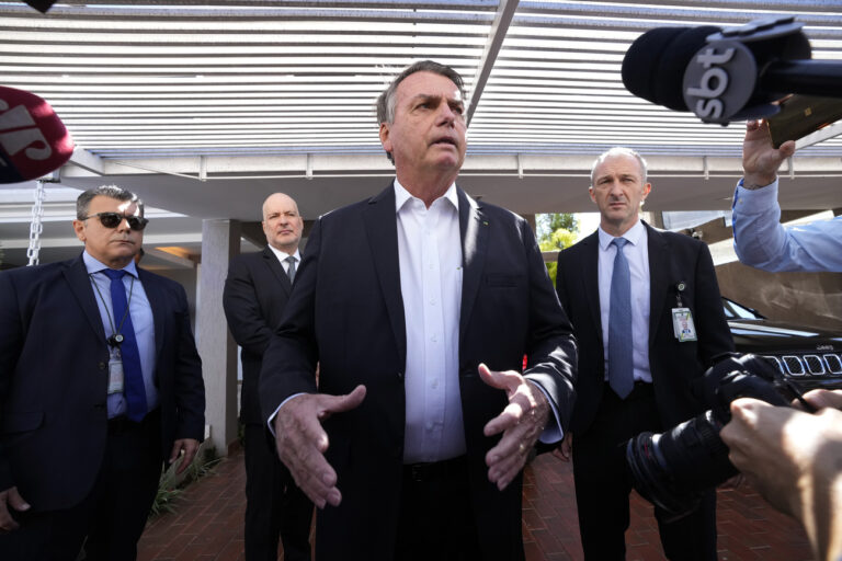 Former Brazilian President Jair Bolsonaro speaks to the press outside his home after Federal Police agents carried out a search and seizure warrant in Brasilia, Brazil, Wednesday, May 3, 2023. When asked about the search of Bolsonaro's home in Brasilia, the Federal Police press office gave a statement saying officers were carrying out searches and arrests related to the introduction of fraudulent data related to the COVID-19 vaccine into the nation's health system. (AP Photo/Eraldo Peres)