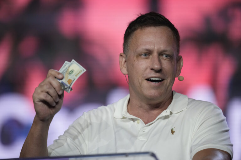 FILE - Peter Thiel, co-founder of PayPal and Palantir, offers a pair of hundred dollar bills to attendees during a keynote address at the Bitcoin Conference, April 7, 2022, in Miami Beach, Fla. Millionaire candidates and billionaire investors are harnessing their considerable personal wealth to try to win competitive Republican primaries for open U.S. Senate seats in Ohio and Pennsylvania. Billionaire tech investor Thiel has poured money into a super PAC backing âÄœHillbilly ElegyâÄ author JD Vance. (AP Photo/Rebecca Blackwell, File)