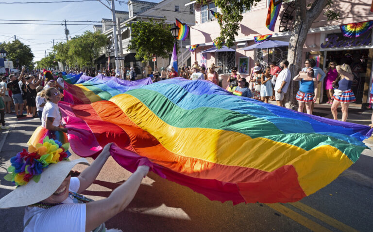 In this photo provided by the Florida Keys News Bureau, marchers in the Key West Pride parade carry a 100-foot-long section of an iconic 1.25-mile-long rainbow flag, Sunday, June 11, 2023, up Duval Street in Key West, Fla. The parade commemorated the 20th anniversary of the flag's 2003 unfurling when it blanketed the entire street from the Gulf of Mexico to the Atlantic Ocean. Called the 