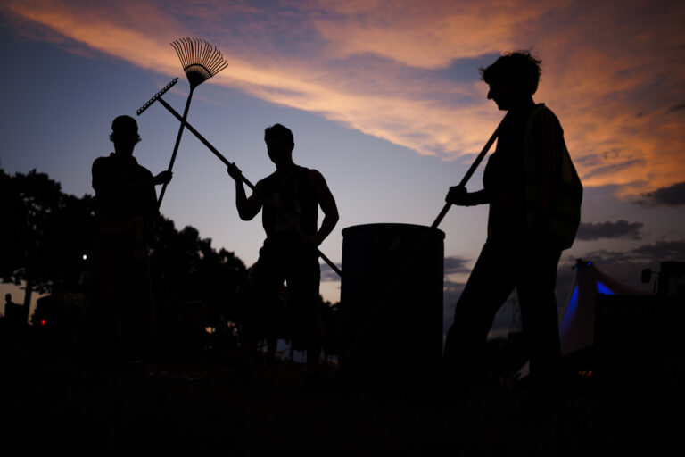 Volunteers pose as they collect trash after festival goers have left the venue, following the opening day of the 46th edition of the Paleo Festival, early Wednesday, July 19, 2023. The Paleo is a open-air music festival in the western part of Switzerland with about 250'000 spectators in six days and will take place from 18th to 23rd July. (KEYSTONE/Valentin Flauraud)