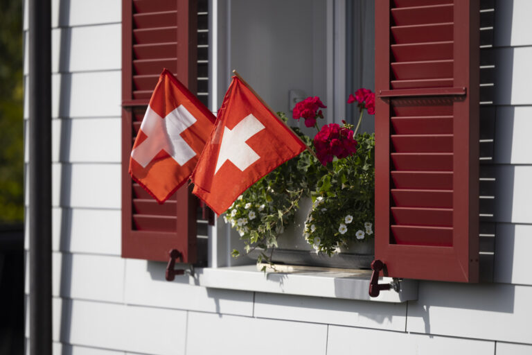 Zwei Schweizer Flaggen wehen in einem Geranientopf auf einem Fensterbrett, am Montag, 31. Juli 2023 in Studen. (KEYSTONE/Peter Klaunzer)