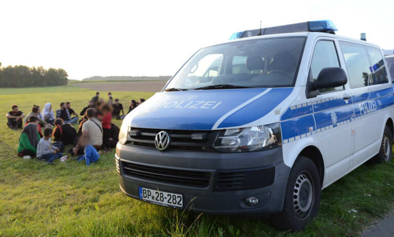 12.09.2023, Sachsen, Oberseifersdorf: Eine Gruppe von Migranten aus Syrien und der Türkei sitzt neben einem Einsatzfahrzeug der Polizei. Die Bundespolizei in Sachsen hat erneut illegal eingereiste Geflüchtete entdeckt. Die 49 Menschen, darunter 20 Kinder, waren wohl mehrere Stunden bei hohen Außentemperaturen in einem Transporter eingesperrt, wie ein Sprecher der Bundespolizeiinspektion Ebersbach mitteilte. (zu dpa: «Bundespolizei findet Geflüchtete in Transporter - 20 Kinder darunter») Foto: Thomas Baier/xcitepress/dpa - ACHTUNG: Person(en) wurde(n) aus rechtlichen Gründen gepixelt +++ dpa-Bildfunk +++ (KEYSTONE/DPA/Thomas Baier)