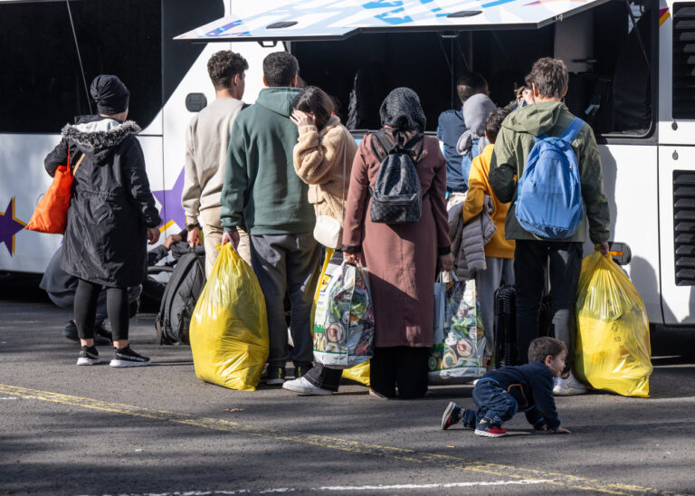 ARCHIV - 11.10.2023, Hessen, Gießen: Flüchtlinge gehen in der hessischen Erstaufnahmeeinrichtung (HEAE) in Gießen zu einem wartenden Bus zur Weiterfahrt in kommunale Einrichtungen. Hessens Regierungschef Boris Rhein (CDU) dringt auf mehr Geld vom Bund zur Versorgung der Schutzsuchenden. - (zu dpa «Vorsitzender der Länderchef-Konferenz fordert mehr Geld für Migranten») Foto: Boris Roessler/dpa +++ dpa-Bildfunk +++ (KEYSTONE/DPA/Boris Roessler)