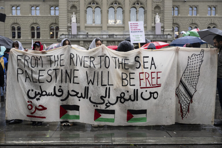 Protesters hold a banner and a placard during a rally in solidarity with Palestine under the slogan 