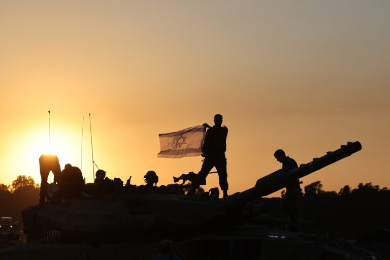 epa11001466 An Israeli soldier holds an Israeli flag while standing on top of a tank during a temporary ceasefire, near the Gaza border, in southern Israel, 29 November 2023. A four-day ceasefire agreed by Israel and Hamas was extended by 48 hours on 27 November, as more talks on a possible extension were ongoing. The Israeli army on 29 November reissued its daily message to the residents of Gaza to avoid moving back into northern Gaza which is considered a 'war zone', to not approach within one kilometer of the border and to not access the sea. Thousands of Israelis and Palestinians have died since the militant group Hamas launched an unprecedented attack on Israel from the Gaza Strip on 07 October, and the Israeli strikes on the Palestinian enclave which followed it. EPA/ABIR SULTAN