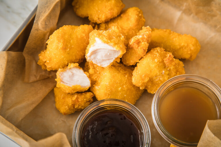 ARCHIV - 02.02.2022, Sachsen, Wittenberge: Chicken Nuggets liegen neben Soßen auf einem Stück Backpapier. Sie sind verzehrfertig, ansprechend verpackt - enthalten oft viel Zucker, Salz, Fett und Zusatzstoffe, aber wenig wichtige Nährstoffe. Stark verarbeitete Lebensmittel landen sehr häufig im Einkaufswagen. Experten sehen Risiken bei hohem Konsum (zu dpa «Häufig aufgetischt, selten gesund: hochverarbeitete Lebensmittel») Foto: Christin Klose/dpa-tmn/dpa +++ dpa-Bildfunk +++ (KEYSTONE/DPA/Christin Klose)