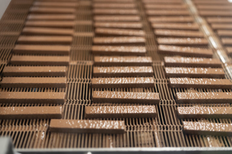 Die frisch mit Schokolade ueberzogenen Waffelstaebchen, Kaegi Fret, kommen aus der Maschine und werden gekuehlt, fotografiert im Kaegi Fret Fabrik am Mittwoch, 7. Februar 2024 in Lichtensteig (SG). (KEYSTONE/Gaetan Bally)