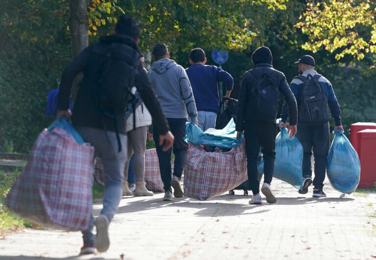 PRODUKTION - 17.10.2023, Hamburg: Flüchtlinge aus Syrien gehen mit ihrem Gepäck zu der Erstaufnahmeeinrichtung in der Schmiedekoppel 30 im Stadtteil Niendorf. (zu dpa: «Hamburg will Zelte für Flüchtlinge notfalls in Parks aufstellen») Foto: Marcus Brandt/dpa +++ dpa-Bildfunk +++ (KEYSTONE/DPA/Marcus Brandt)