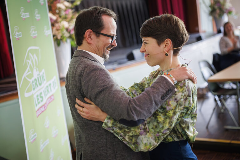 Lisa Mazzone (droite), candidate a la presidence des Verts suisses felicite Balthasar Glaettli (gauche), president sortant des Verts suisses, lors de l'assemblee des delegues des Verts ce samedi 6 avril 2024 a Renens. (KEYSTONE/Valentin Flauraud)