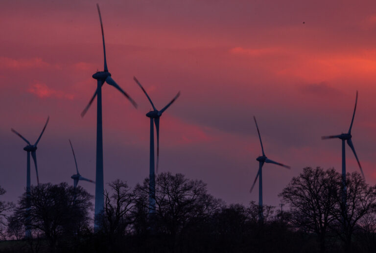 ARCHIV - 12.02.2024, Mecklenburg-Vorpommern, Gadebusch: Die Rotorblätter von Windkraftanlagen drehen sich vor dem orangerot eingefärbtem Abendhimmel. Die Genehmigungsverfahren für Windkraftanlagen dauern einer Studie der Fachagentur Windenergie zufolge in keinem Bundesland so lange wie in Mecklenburg-Vorpommern. (zu dpa: «Studie: Windrad-Genehmigungen dauern in MV am längsten») Foto: Jens Büttner/dpa +++ dpa-Bildfunk +++ (KEYSTONE/DPA/Jens Büttner)