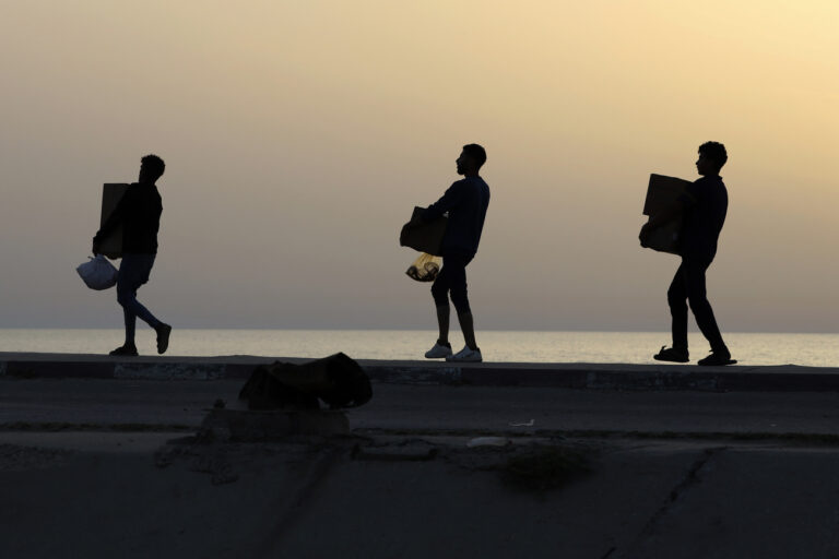 Palestinians carry aid boxes after storming trucks loaded with humanitarian aid brought in through a new U.S.-built pier, at the beach road of Nusseirat refugee camp, central Gaza Strip, Saturday, May 18, 2024. (AP Photo/Saher Alghorra)