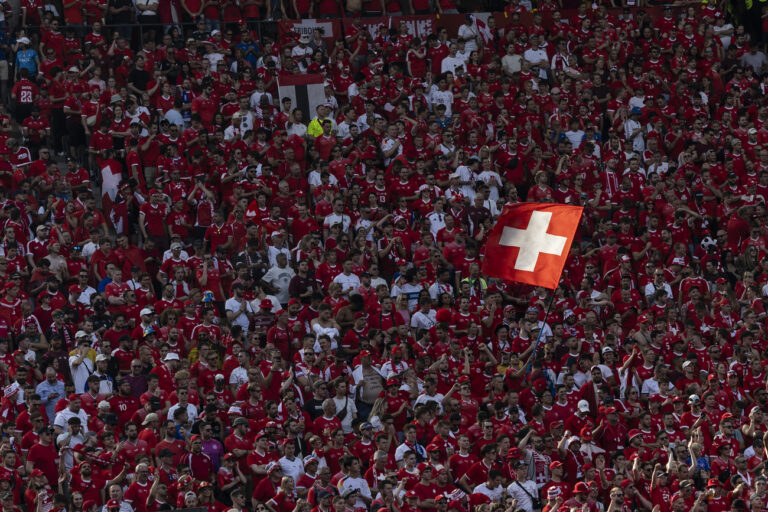 A fan in the Swiss sector flies a Swiss flag during a round of 16 soccer match between Switzerland and Italy at the Euro 2024 soccer tournament in Berlin, Germany, Saturday, June 29, 2024. (KEYSTONE/Peter Klaunzer)