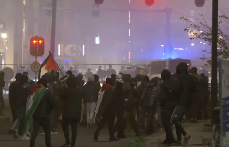 In this image taken from video, a group of pro-Palestinian protesters walk toward police line, with police vans driving in the background, near the soccer stadium in Amsterdam, Netherlands, Thursday, Nov. 7, 2024. (RTL Nieuws via AP)