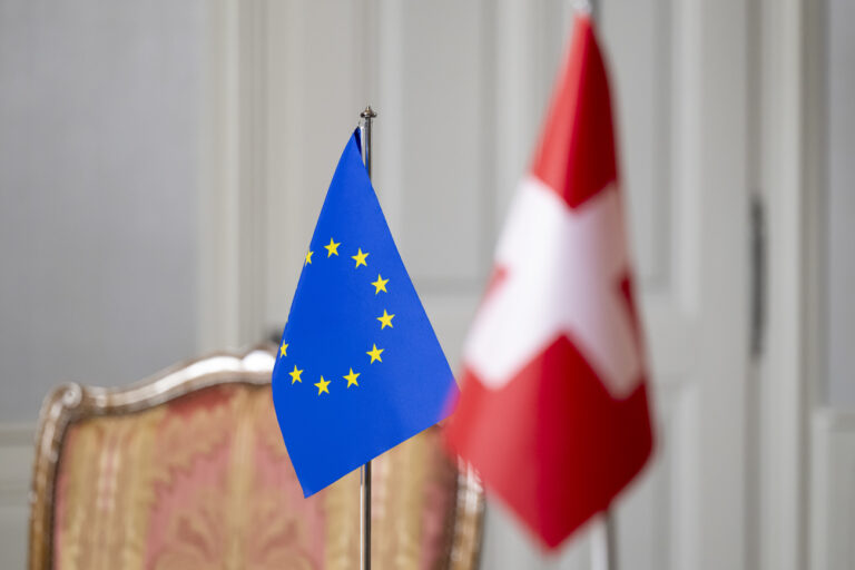 A Swiss flag, right, and an European flag, left, stand in a room prior to a working visit by Swiss Federal Councillor Ignazio Cassis to Maros Sefcovic, Vice-President of the European Commission, at the Lohn country residence of the Swiss government, on Wednesday, November 27, 2024, in Kehrsatz near Bern, Switzerland. (KEYSTONE/Anthony Anex)