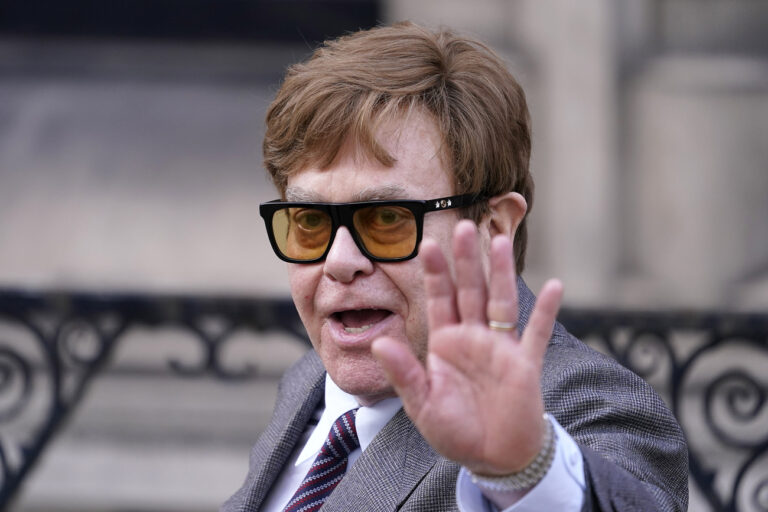 FILE - Elton John waves to the waiting media as he leaves the Royal Courts Of Justice in London, Monday, March 27, 2023. (AP Photo/Alberto Pezzali, File)