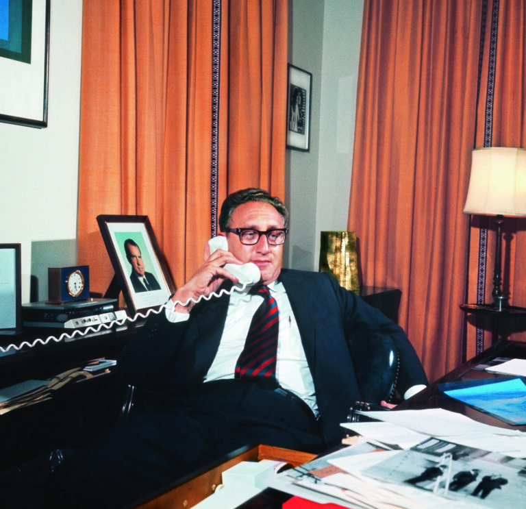 Der amerikanische Politiker Henry Kissinger in seinem Buero im Weissen Haus, Washington, USA, undatierte Aufnahme. Kissinger, als Sohn deutsch-juedischer Emmigranten, geboren 1923, bestimmte 1969-1975 als Sicherheitsberater und 1973-1977 als Aussenminister massgeblich die US-Aussenpolitik unter den Praesidenten Richard Nixon und Gerald Ford. Im Hintergrund ist ein Foto von Richard Nixon sichtbar. (KEYSTONE/CAMERA PRESS/Tom Blau) === === : DIA, Mittelformat]
